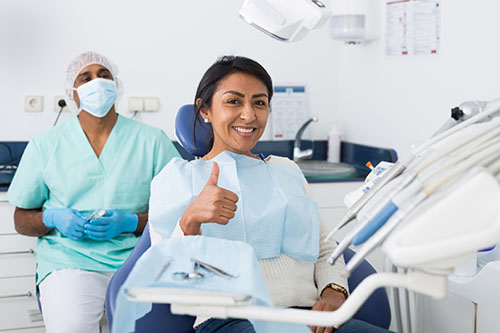 Happy woman sitting in dental chair after teeth cure in clinic Yorkson Dentist With Patient