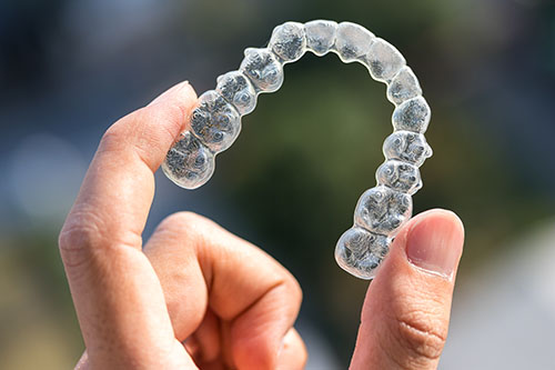 Holding invisalign braces on bokeh background Yorkson Dentist With Patient