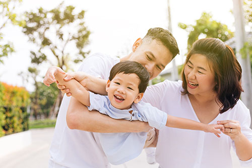 Asian family having fun and carrying a child in public park Yorkson Dentist With Patient
